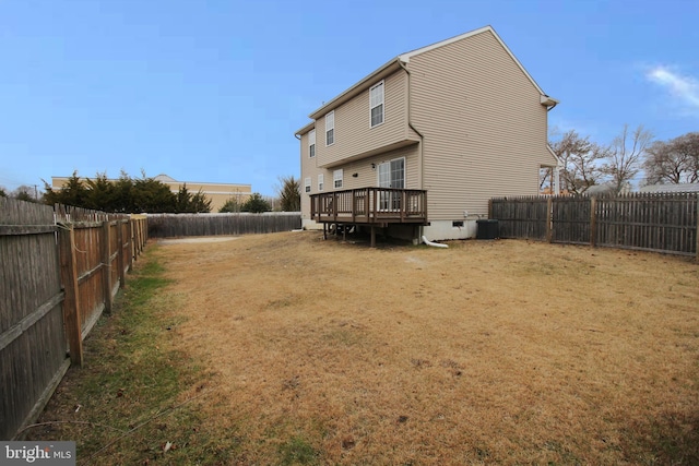 rear view of property featuring central AC unit, a lawn, and a deck