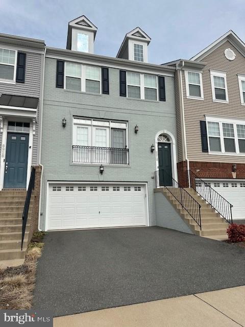 townhome / multi-family property featuring brick siding, an attached garage, and aphalt driveway