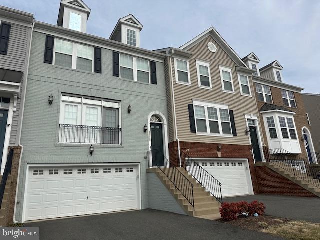 multi unit property with a garage, brick siding, and aphalt driveway