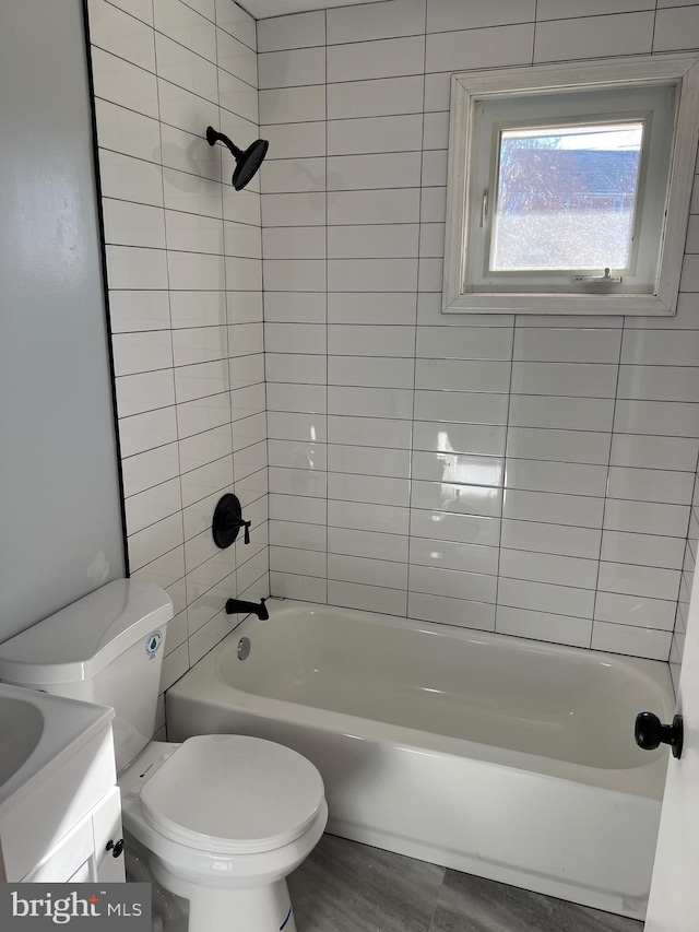 full bathroom featuring tiled shower / bath, vanity, and toilet