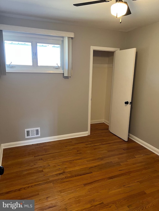 unfurnished bedroom with wood-type flooring, ceiling fan, and a closet