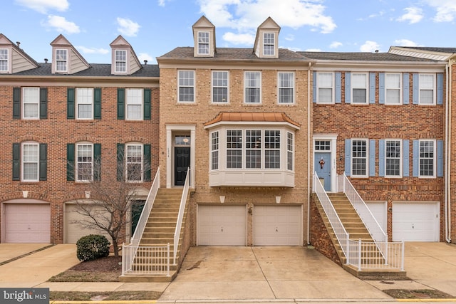 view of property with a garage, concrete driveway, brick siding, and stairs