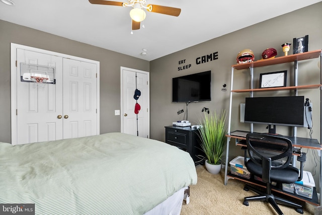 bedroom with carpet floors, ceiling fan, and two closets