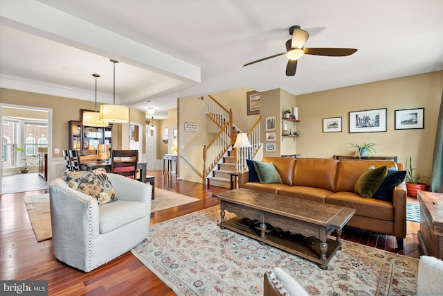 living area with ornamental molding, stairway, wood finished floors, and a ceiling fan