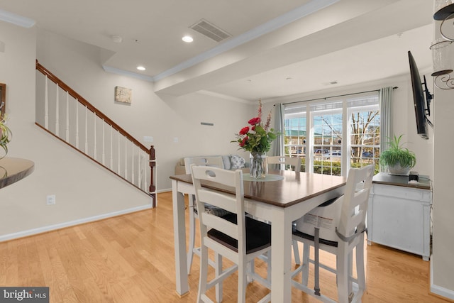 dining space with ornamental molding and light hardwood / wood-style flooring