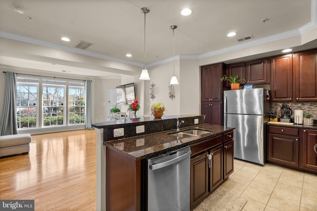 kitchen with dark stone countertops, sink, decorative light fixtures, stainless steel appliances, and decorative backsplash