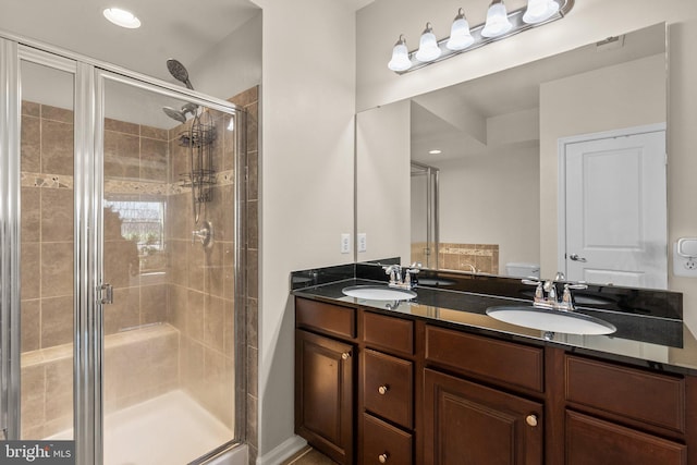 bathroom with toilet, vanity, and a shower with shower door