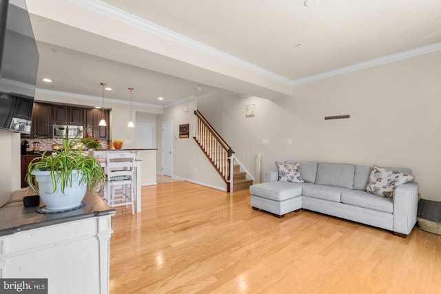 living room with ornamental molding and light hardwood / wood-style floors