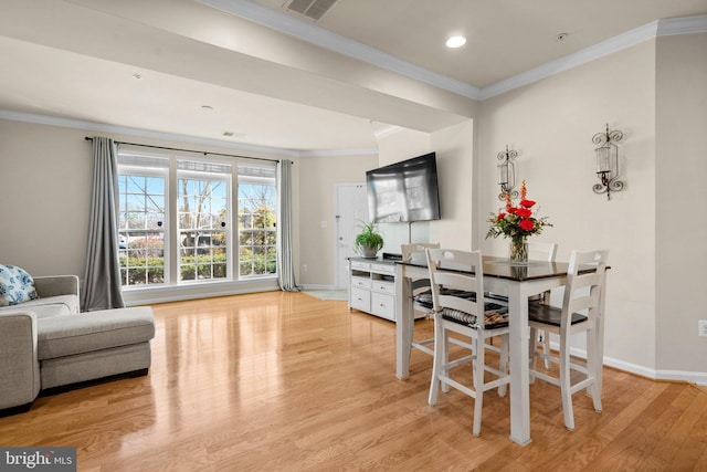 dining area featuring ornamental molding and light hardwood / wood-style flooring