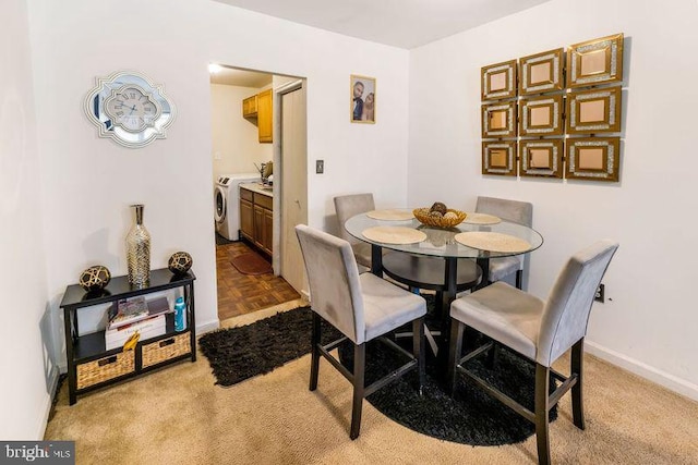 dining area with light carpet, baseboards, and washer and dryer