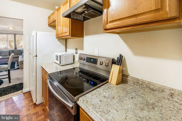 kitchen with light stone countertops, under cabinet range hood, stainless steel electric range oven, and white microwave