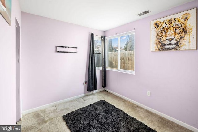 spare room featuring carpet floors, visible vents, and baseboards