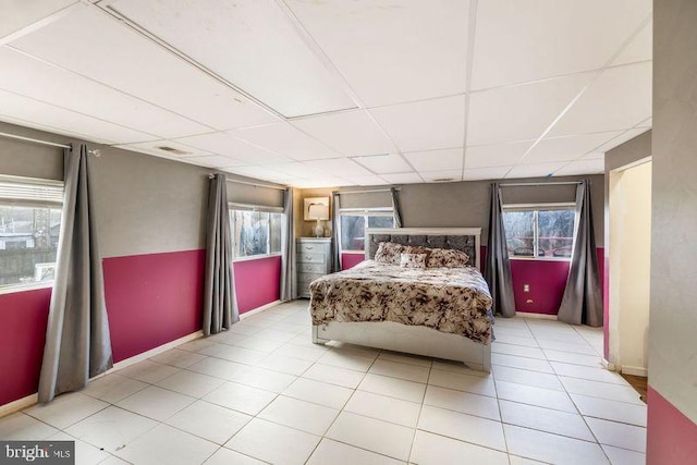 bedroom with a drop ceiling, light tile patterned flooring, and baseboards