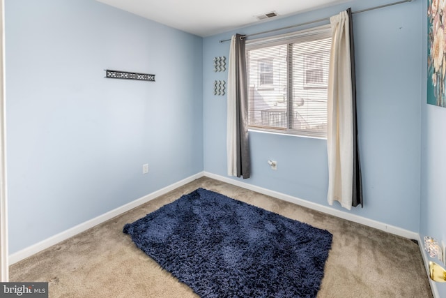 empty room with carpet floors, visible vents, and baseboards