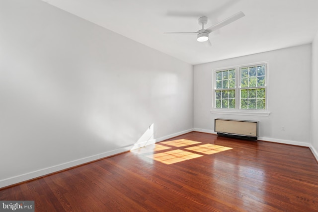 unfurnished room with dark hardwood / wood-style floors, radiator heating unit, and ceiling fan