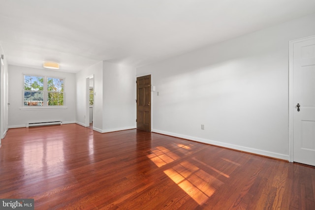 spare room with dark wood-type flooring and a baseboard heating unit