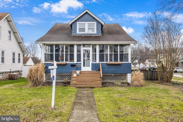 bungalow-style home with a front lawn and a sunroom