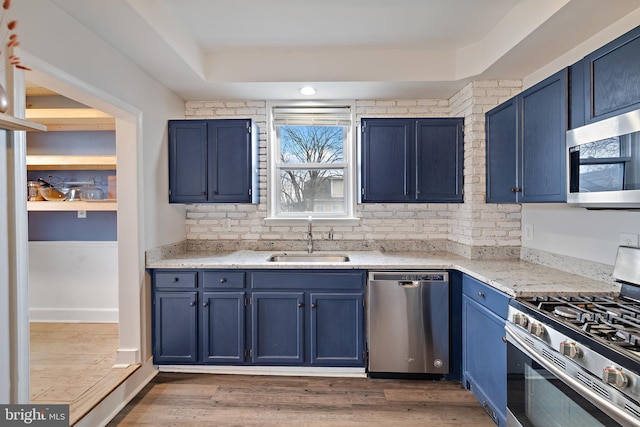 kitchen with blue cabinets, light stone countertops, appliances with stainless steel finishes, and sink