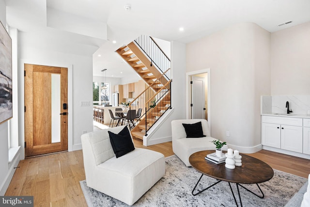 living area with visible vents, baseboards, recessed lighting, stairs, and light wood-style floors