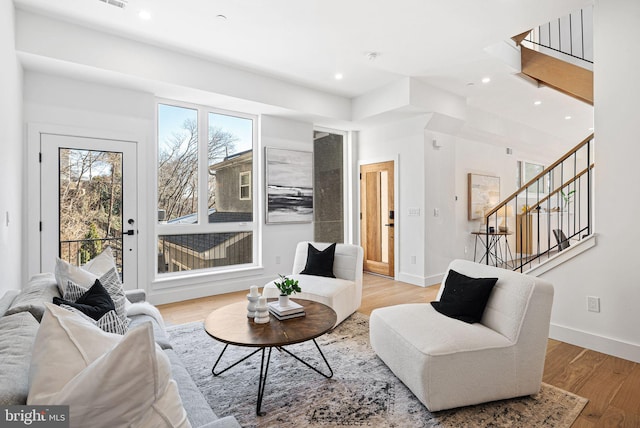 living room featuring stairway, recessed lighting, baseboards, and light wood finished floors