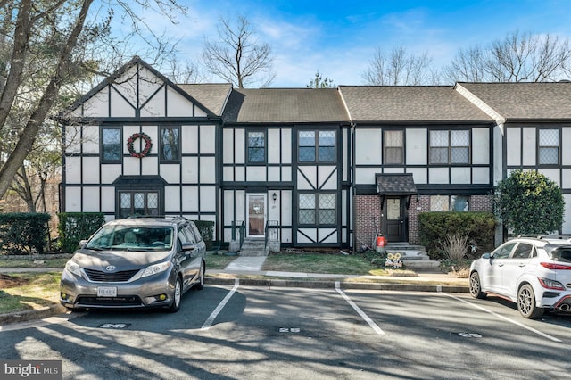 view of front of home featuring brick siding, stucco siding, a shingled roof, and uncovered parking