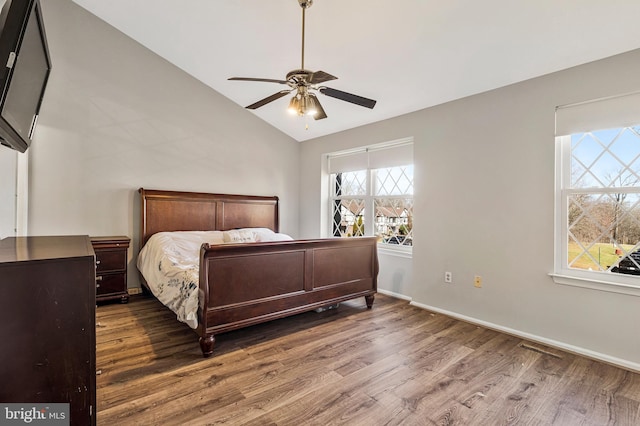 bedroom featuring lofted ceiling, wood finished floors, baseboards, and ceiling fan