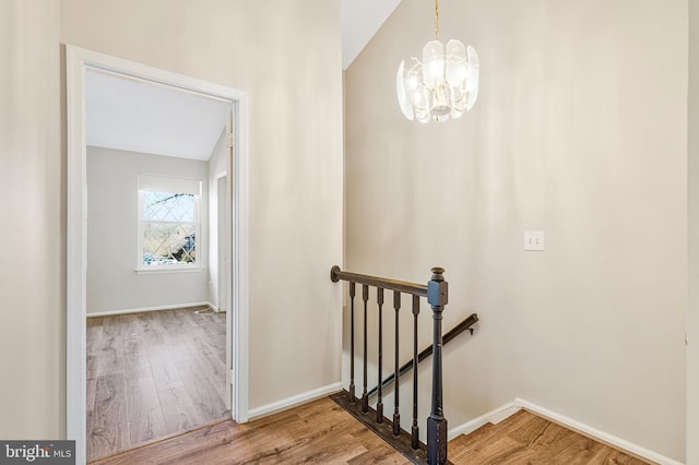 stairway with a notable chandelier, baseboards, and wood finished floors