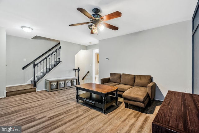 living room with wood finished floors, ceiling fan, and stairs