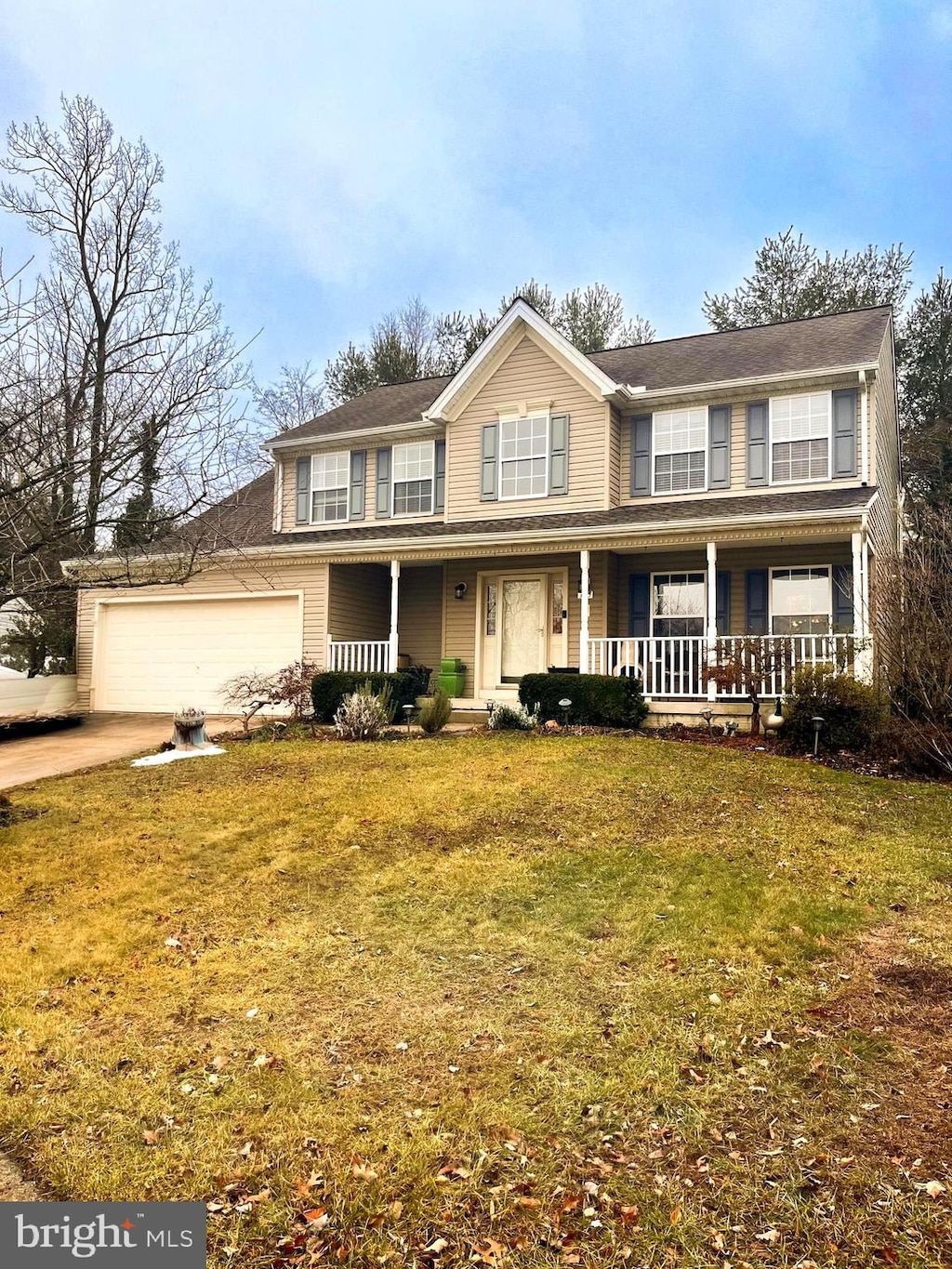 view of front of house with covered porch, a front yard, and a garage