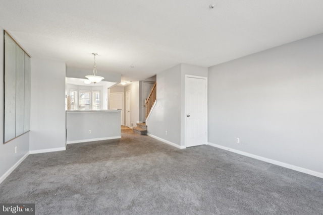 unfurnished living room featuring carpet floors, stairway, and baseboards