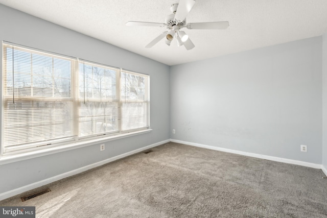 empty room featuring a textured ceiling, carpet floors, visible vents, and baseboards