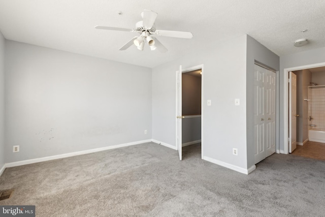 unfurnished bedroom with baseboards, ensuite bath, a textured ceiling, carpet flooring, and a closet