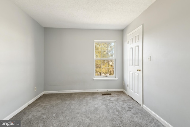 unfurnished room with carpet floors, visible vents, baseboards, and a textured ceiling