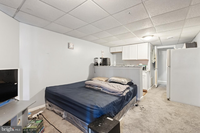 bedroom featuring light carpet, baseboards, a paneled ceiling, and freestanding refrigerator