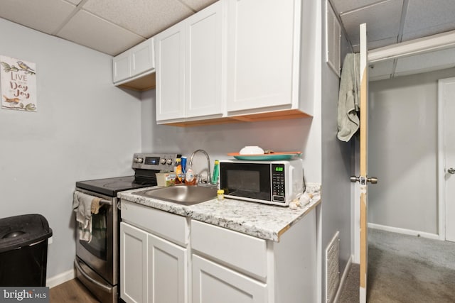 kitchen featuring stainless steel range with electric stovetop, white cabinetry, and a sink