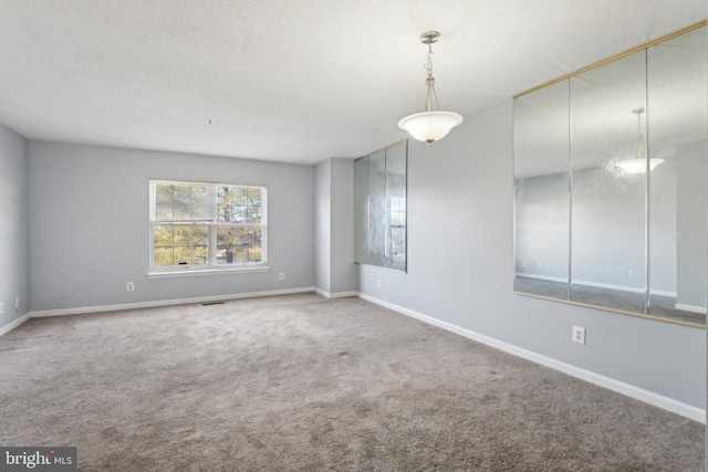 carpeted spare room with visible vents, a textured ceiling, and baseboards