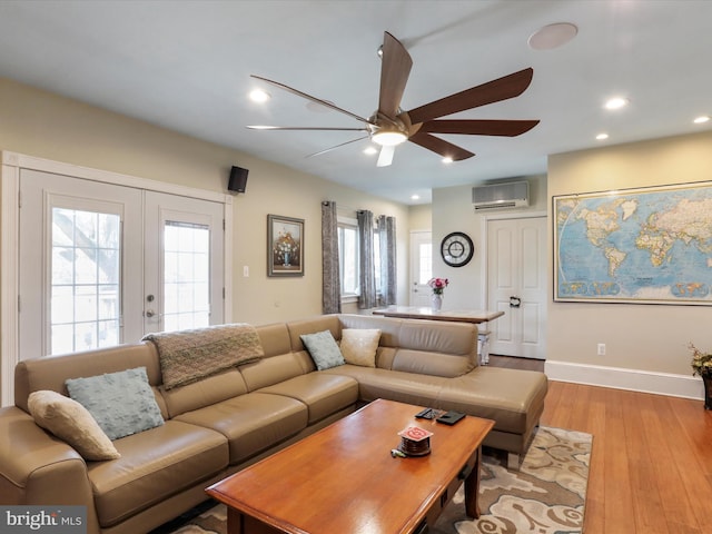 living room with a wall unit AC, french doors, ceiling fan, and light hardwood / wood-style flooring