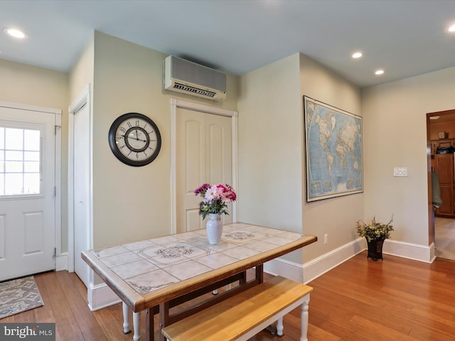 dining area featuring an AC wall unit and light hardwood / wood-style flooring