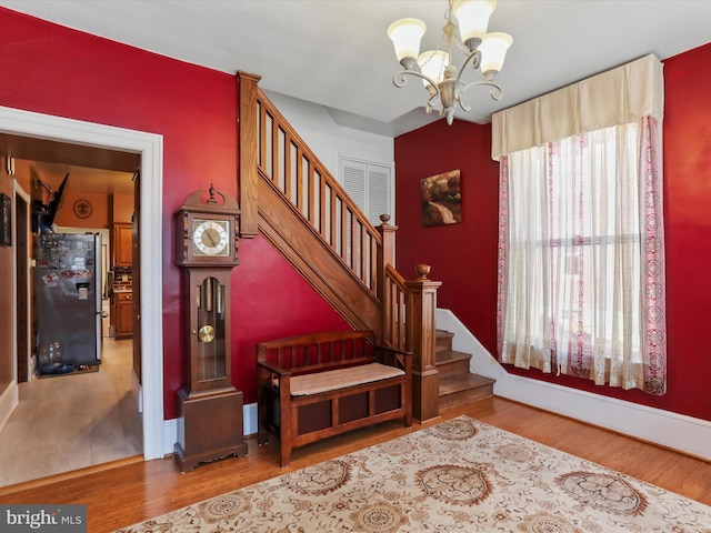 stairs with hardwood / wood-style flooring, an inviting chandelier, and a wealth of natural light