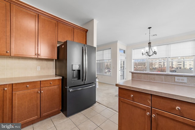 kitchen featuring brown cabinets, light tile patterned floors, tasteful backsplash, hanging light fixtures, and refrigerator with ice dispenser