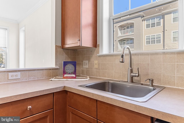 kitchen featuring ornamental molding, light countertops, and a sink