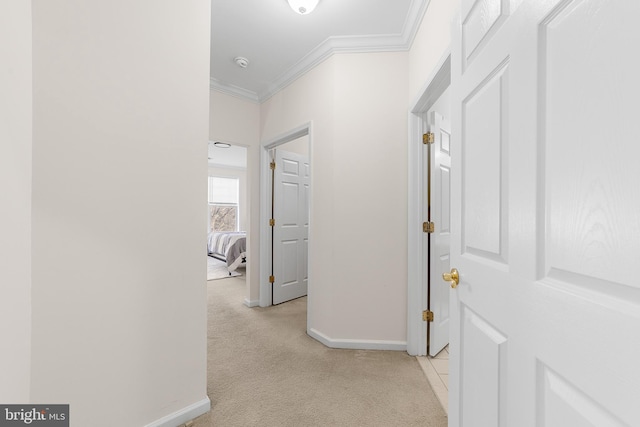 hall with light carpet, crown molding, and baseboards