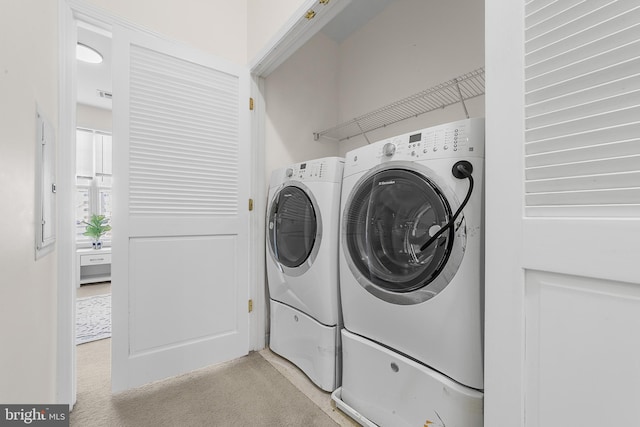 clothes washing area with laundry area, light colored carpet, and washing machine and clothes dryer