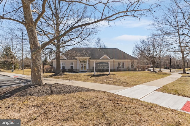 view of front facade featuring roof with shingles, french doors, and a front lawn