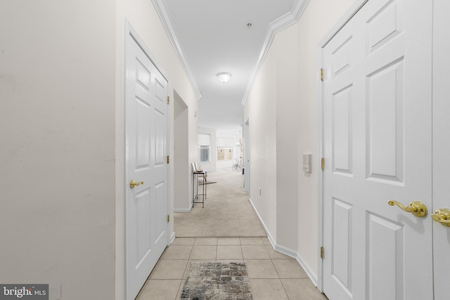 hallway featuring light tile patterned flooring, crown molding, light carpet, and baseboards