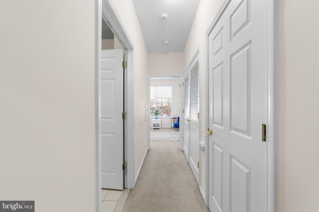 hall featuring baseboards and light colored carpet