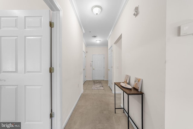 hallway with ornamental molding, light carpet, visible vents, and baseboards