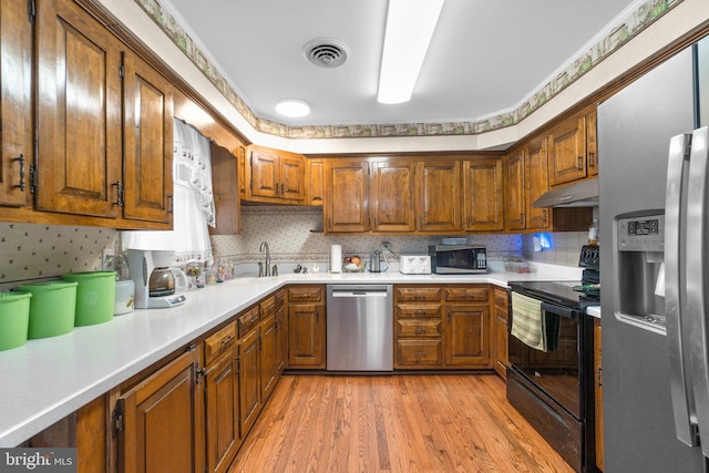 kitchen featuring brown cabinets, stainless steel appliances, visible vents, light countertops, and under cabinet range hood