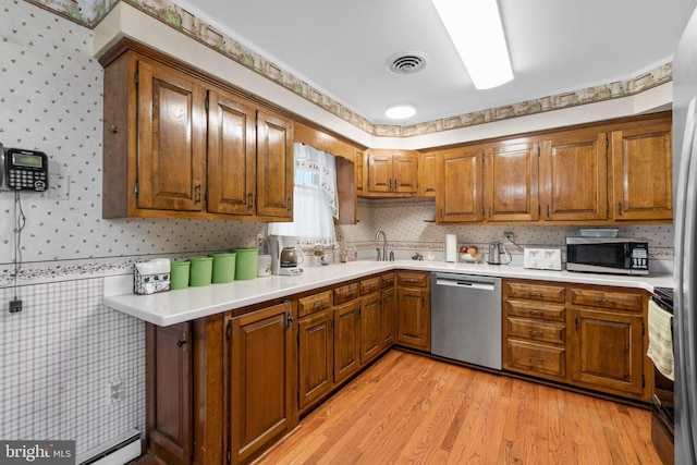 kitchen with wallpapered walls, visible vents, appliances with stainless steel finishes, brown cabinets, and light countertops