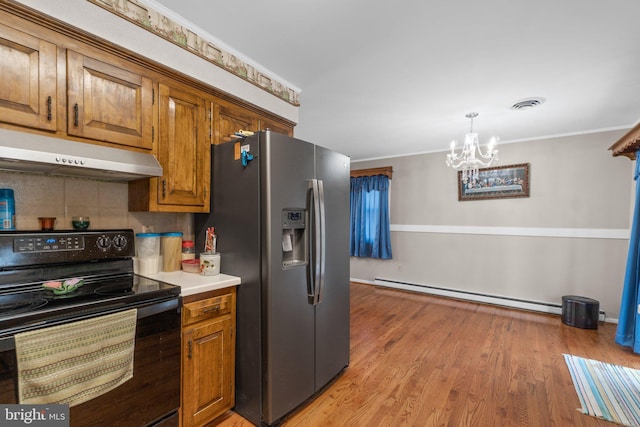 kitchen featuring stainless steel fridge, black range with electric stovetop, baseboard heating, light countertops, and under cabinet range hood